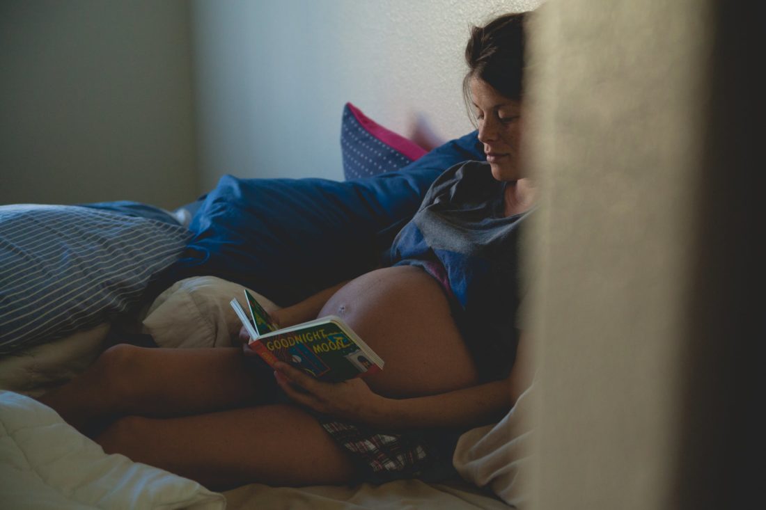 future maman lit un livre de bébé